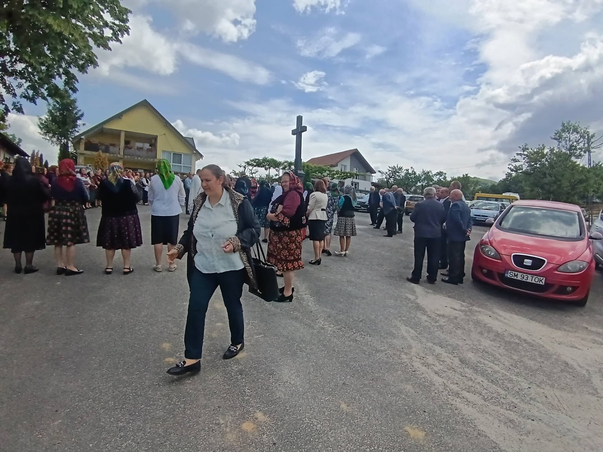 Oameni adunați pe o stradă dintr-o localitate, într-o zi senină