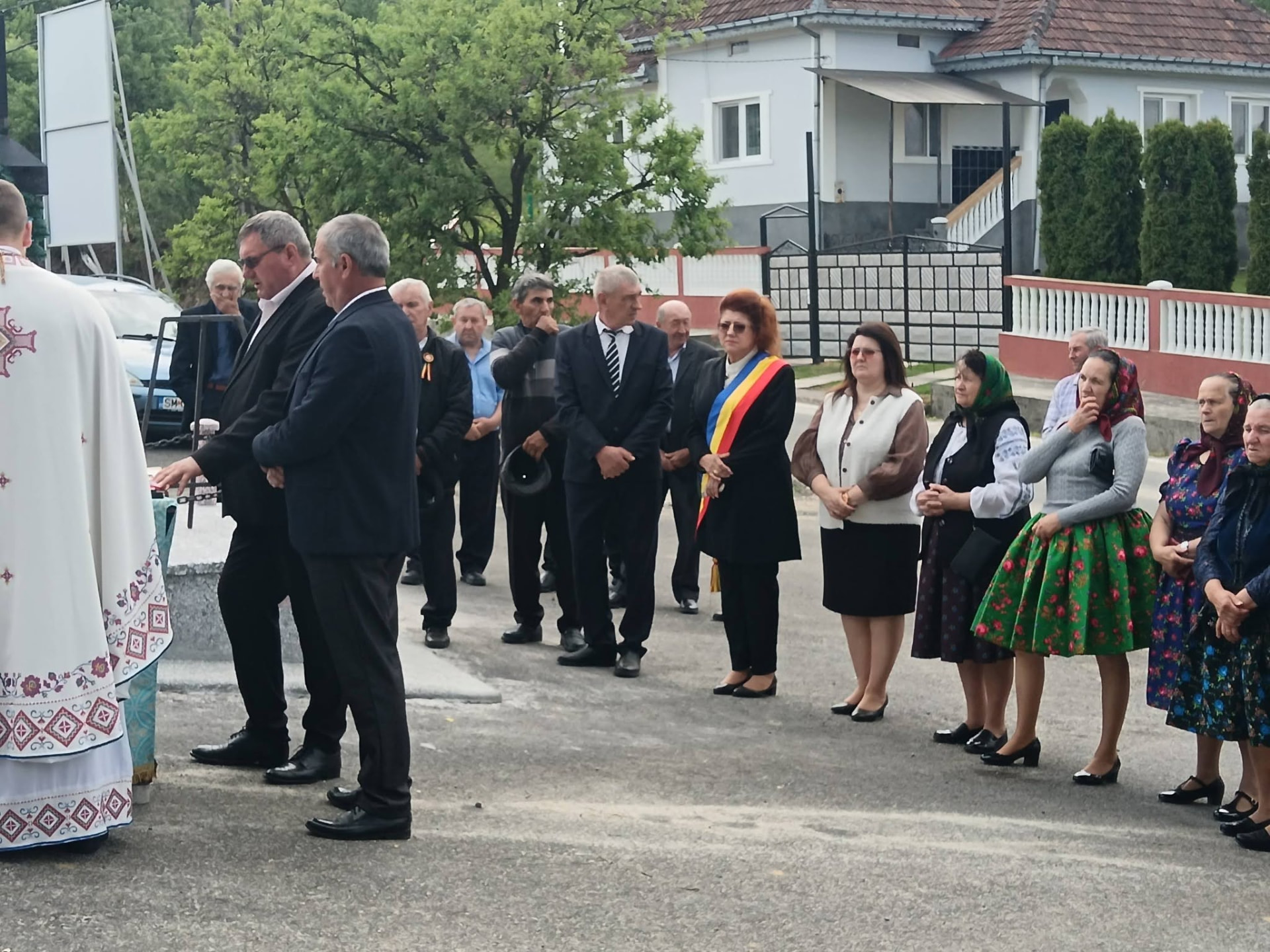 Participanți la o ceremonie în aer liber, unii purtând costume tradiționale